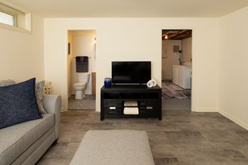 A living room with a grey couch and a black television.